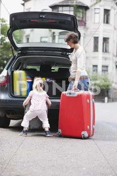 Germany, Leipzig, Mother and daughter (4-5) loading luggage into car Stock Photos