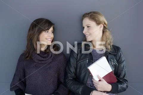 Germany, Leipzig, Young women standing face to face, smiling Stock Photos