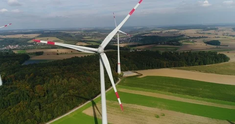 Germany location. The copter shot of wind turbines rotating in golden field Stock Footage 87475504