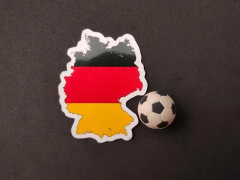 A Germany map sticker showing its flag colors is placed next to a miniature.. Stock Photos