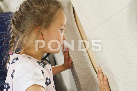 Germany, Munich, Bavaria, Girl looking through window in economy class airliner Stock Photos