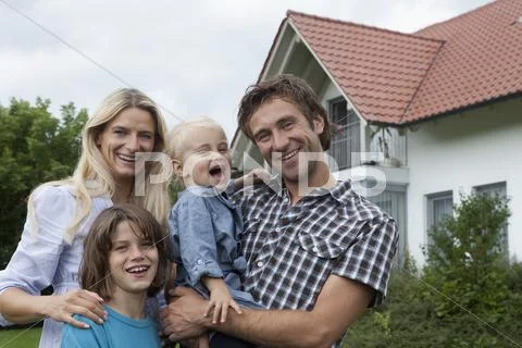 Germany, Munich, Family Standing In Front Of House, Smiling, Portrait