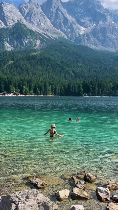 Germany, Munich, July 29, 2025: Summertime Swimming Fun in Clear Lake Surrounded Stock Footage 314390193