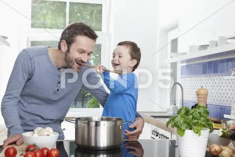 Germany, Munich, Son (2-3 Years) feeding meal to father Stock Photos