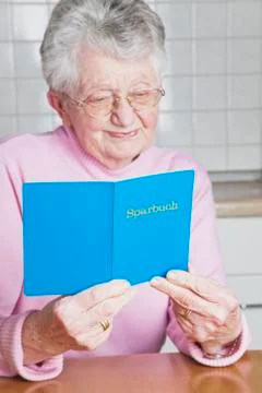Germany, Senior woman holding savings book, smiling Stock Photos
