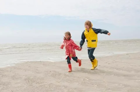 Germany, St. Peter-Ording, North Sea, Boy and girl (6-9) holding hands and Stock Photos