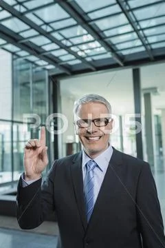 Germany, Stuttgart, Businessman with one finger, smiling, portrait Stock Photos