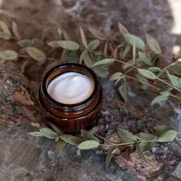 Gesichts- oder Körpercreme im dunklen Glastiegel mit natürlichen Extrakten. Stock Photos