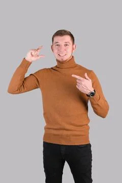 The gesture is small in size. A red-bearded hipster man in a red sweater show Stock Photos