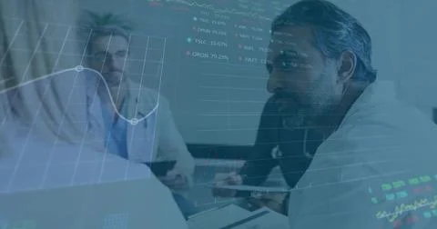 Gesturing bearded man in lab coat leading meeting at clinic, referencing tablet Stock Photos