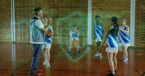 Gesturing coach instructing team dribbling and holding basketballs on gym court Stock Photos