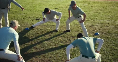 Gesturing coach leading Diverse baseball team doing cone lunges and high knees Stock Footage 336535036