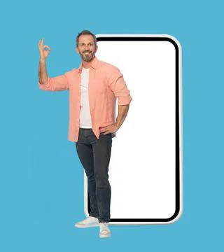 Gesturing OK standing in front big smartphone with white screen handsome middle Stock Photos