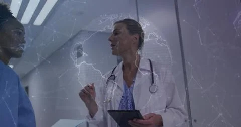 Gesturing physician in white coat with tablet sharing data in clinic, globe Stock Photos