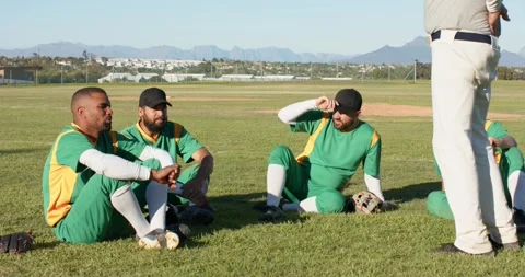 Gesturing senior coach prompting baseball team turning toward him at outfield, Stock Footage 339556773