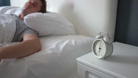 Get up early in morning on clock. Sleeping man reluctantly wakes up to alarm Stock Footage 159213181