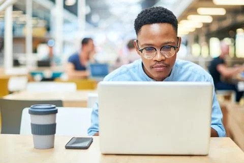 Get focused, get it done. a young businessman using a laptop in a modern office. Stock Photos