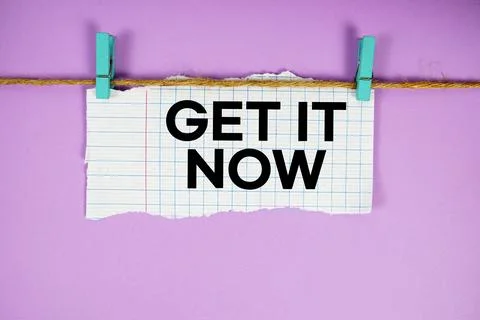 Get It Now text written on rip paper with wooden clip on pink background Stock Photos
