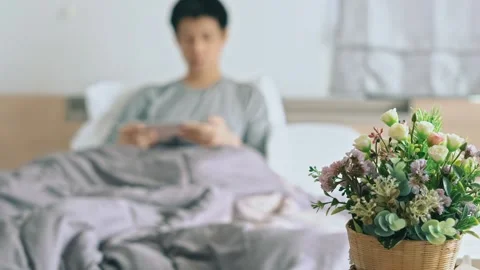 Get Well soon, A man is sleeping on a bed with a bouquet of flowers next to him Stock Footage 314221589