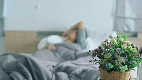 Get Well soon, A man is sleeping on a bed with a bouquet of flowers next to him Stock Footage 314449995
