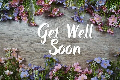 Get Well Soon text message with flowers decoration on wooden background Stock Photos