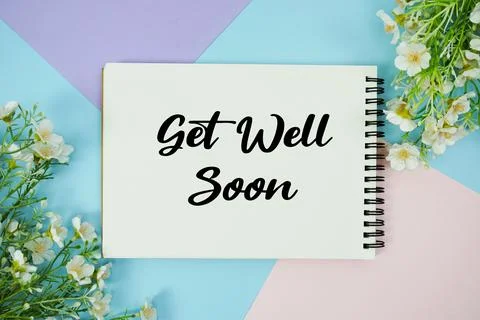 Get Well Soon text written on notepad with flowers decorations flat lay on .. Stock Photos