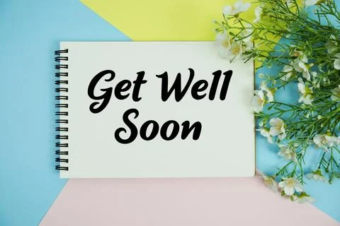 Get Well Soon text written on notepad with flowers decorations flat lay on .. Stock Photos