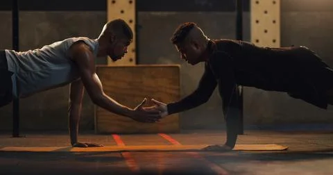 Getting into action to get stronger. two young men doing pushups together in a Stock Photos