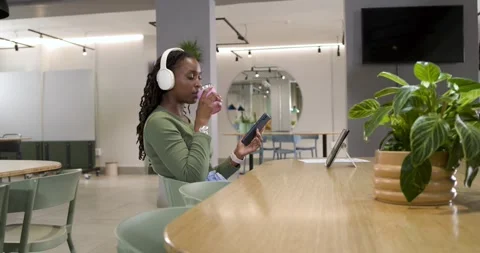 Getting alert, African woman checking phone or tablet for work, sipping cup at Stock Footage 335867283