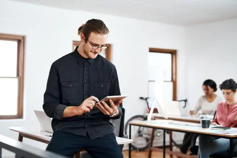 Getting business done, one task at a time. a handsome young businessman using a Stock Photos