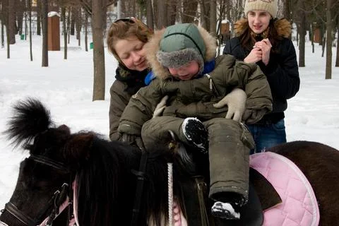 Getting the child on the donkey at winter Stock Photos