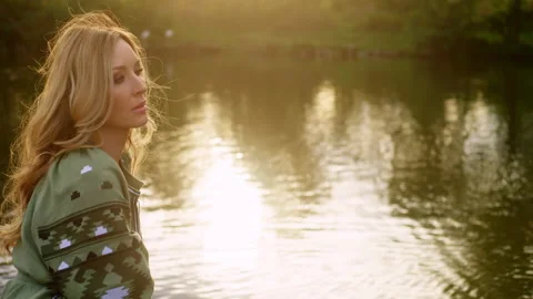 Getting close to a sad beautiful young woman sitting at the river Stock Footage 229774174