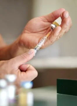 Getting the competitive edge. Closeup of a man filling a syringe with a clear Photos