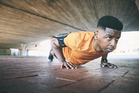Getting fit is a moving experience. a young man doing pushups against an urban Stock Photos