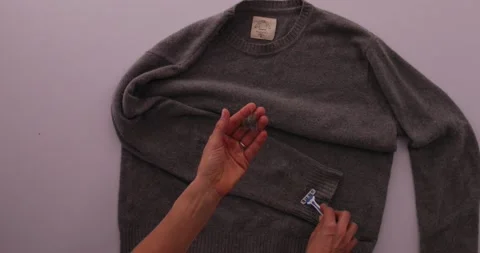Getting fuzz off of a sweater with a razor blade Stock-Footage 132219023