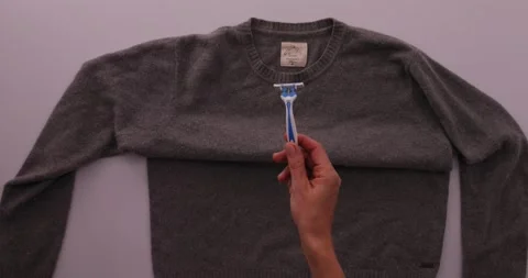 Getting fuzz off of a sweater with a razor blade Stock-Footage 132219031