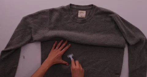 Getting fuzz off of a sweater with a razor blade Stock-Footage 132219037