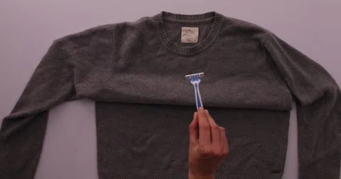 Getting fuzz off of a sweater with a razor blade Stock-Footage 132219096