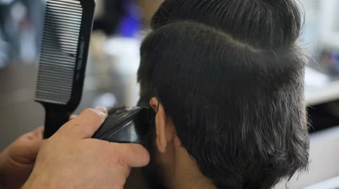 Getting groomed. Shot of a handsome bearded barber giving a haircut to his Stock Footage 62934866