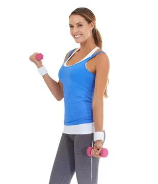 Getting her arms in shape. Fit young woman smiling while using dumbbells against Stock Photos