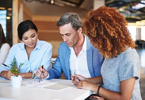 Getting his opinion on their work. smiling colleagues working together in an Stock Photos