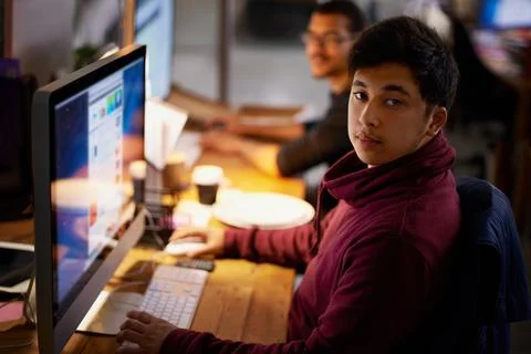 Getting the job done. a group of young coworkers working in a dimly-lit office. Stock Photos