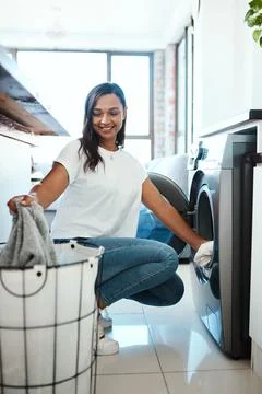 Getting the laundry done before it piles up. Shot of a young woman using a Stock Photos