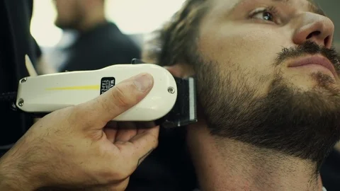 Getting perfect shape. Close-up side view of young bearded man getting beard Stock Footage 69766780