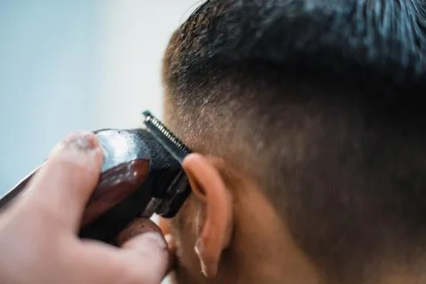 Getting perfect shape. Close-up side view of young bearded man getting beard  Stock Photos