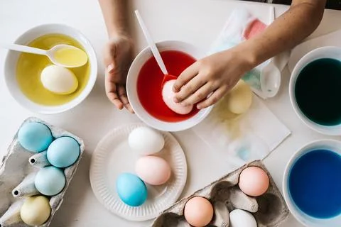 Getting ready concept. Close up child hands dips eggs in liquid dye. Coloring Stock Photos
