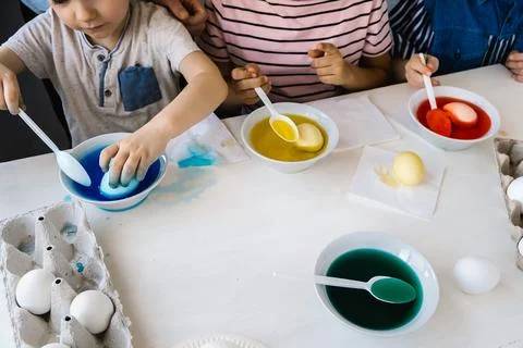 Getting ready concept. Close up children dips eggs in liquid dye. Coloring Stock Photos