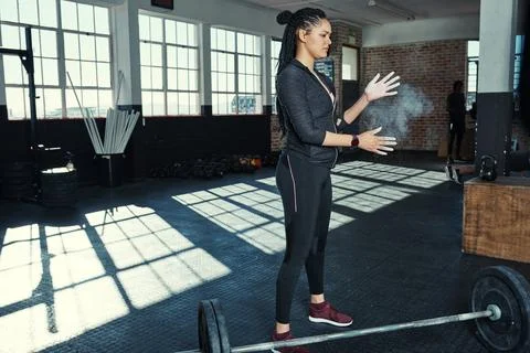 Getting ready to lift some weights. a young woman dusting her hands with chalk Stock Photos