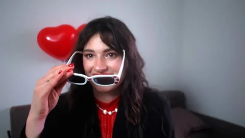 Getting ready for a Valentine's Day party, putting on heart-shaped glasses and d Stock Footage 298185722