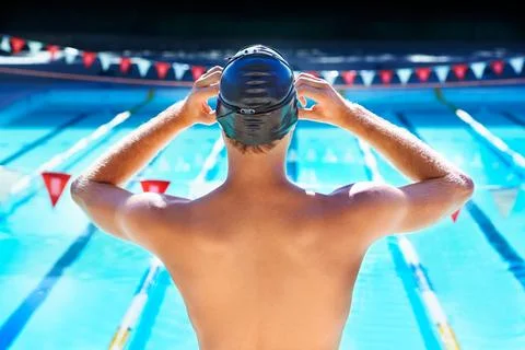 Getting ready to win. Cropped rear view of a male swimmer adjusting his swimming Stock Photos